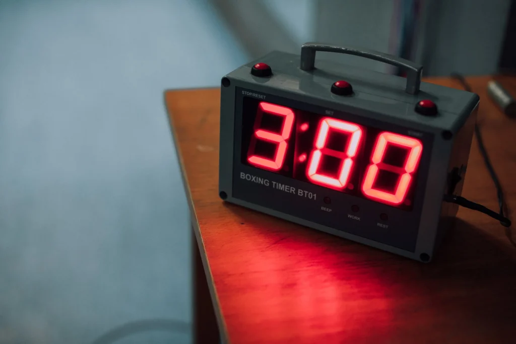 A red alarm clock on a wooden table in a women's-only gym.